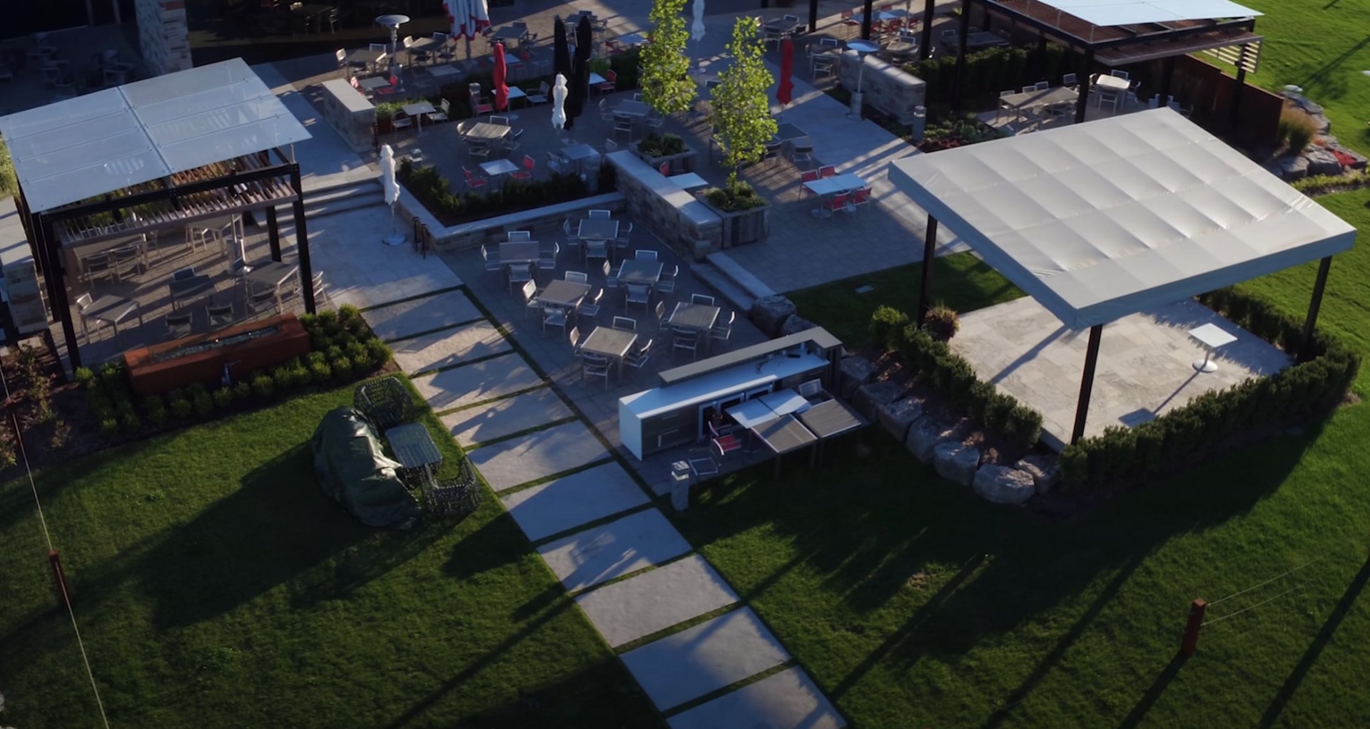 Luxury Backyard Design with Outdoor Kitchen and Pool Area Aerial view of modern backyard with outdoor kitchen, dining area, swimming pool, pergola structures, and manicured lawn creating an entertainment space