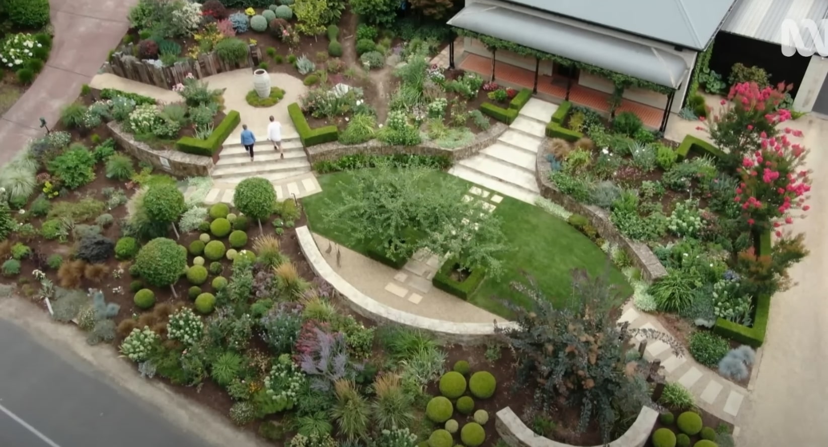 Award-Winning Landscape Architecture and Garden Design Aerial view of elaborate garden design with curved pathways, geometric lawn areas, diverse plantings, topiary spheres, and multi-level landscape architecture
