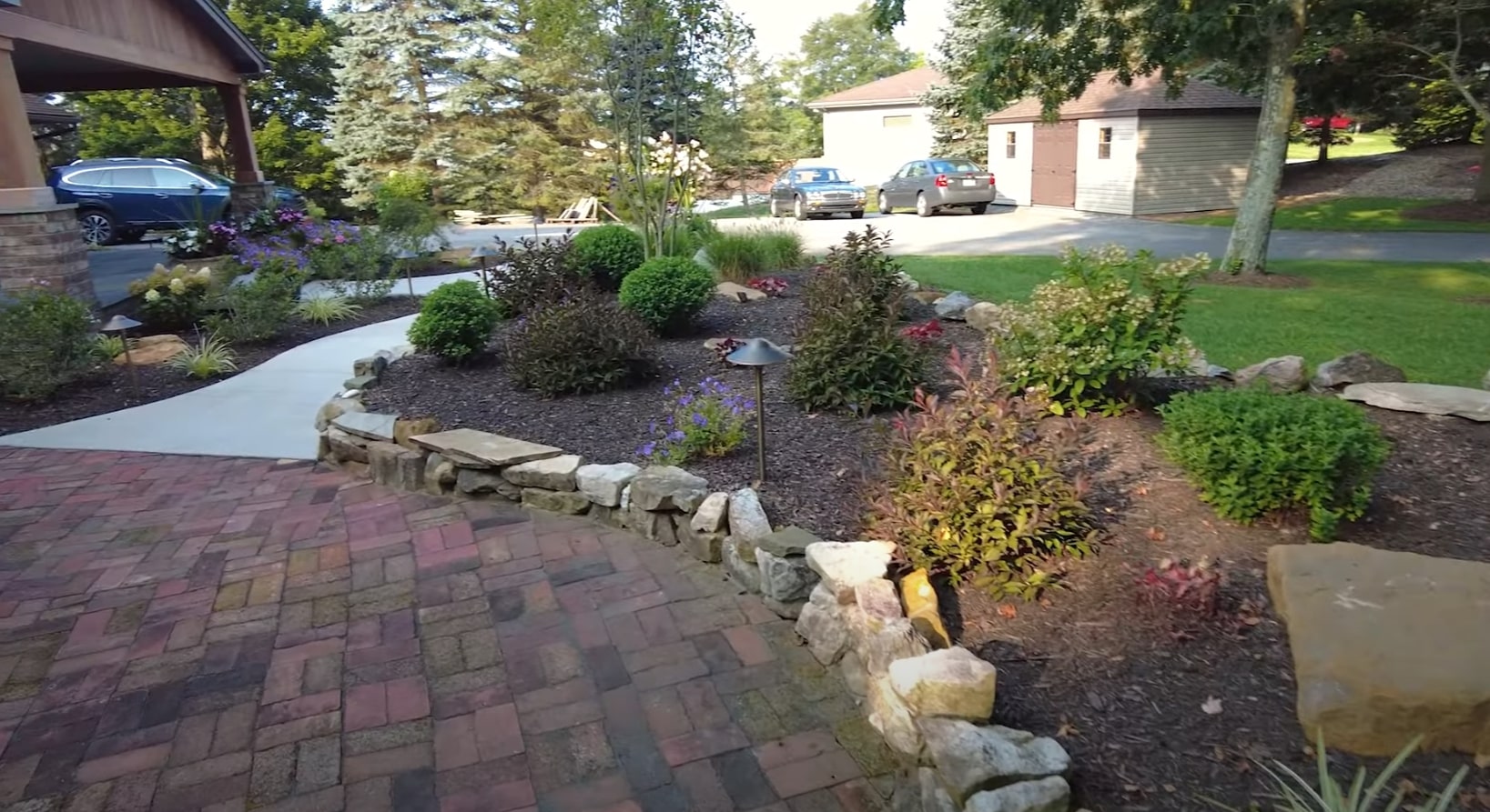Landscape Design and Installation Services Front yard landscape design with decorative stones, planted beds, and professional hardscaping